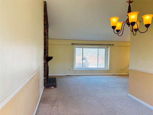 spare room featuring baseboards, a wood stove, an inviting chandelier, and carpet floors