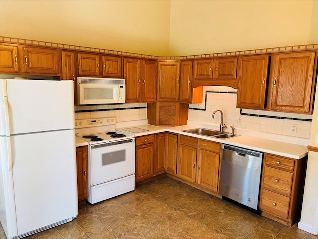 kitchen with a sink, white appliances, and brown cabinets