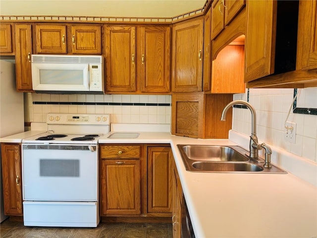 kitchen with white appliances, brown cabinets, backsplash, and a sink