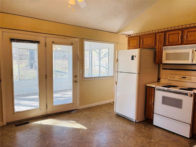 kitchen featuring backsplash, a textured ceiling, white appliances, brown cabinetry, and lofted ceiling