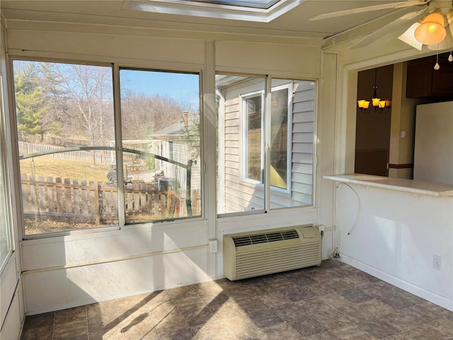 unfurnished sunroom featuring ceiling fan with notable chandelier, a wealth of natural light, and a wall mounted AC