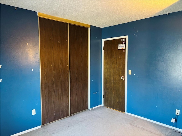 unfurnished bedroom with baseboards, a closet, carpet floors, and a textured ceiling