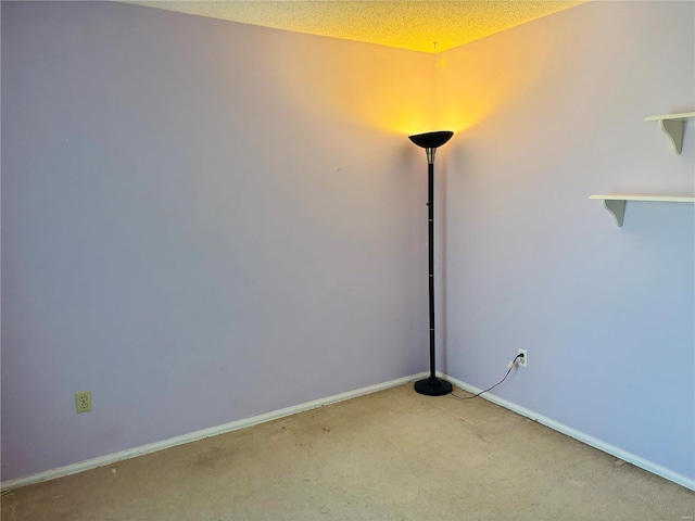 carpeted spare room featuring baseboards and a textured ceiling