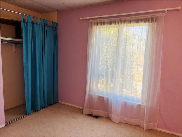 unfurnished bedroom with visible vents, carpet, and a closet