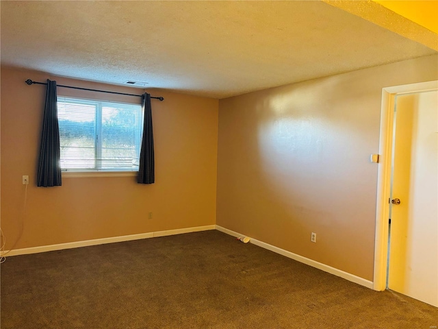 spare room featuring visible vents, baseboards, a textured ceiling, and dark carpet