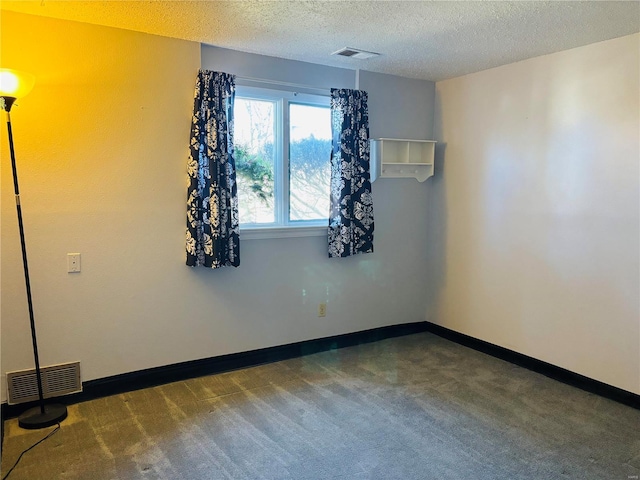 spare room with visible vents, a textured ceiling, carpet, and baseboards