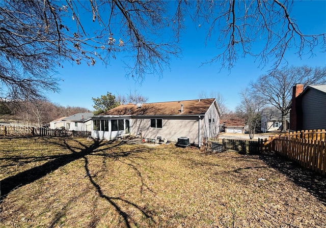 back of house featuring a lawn, a fenced backyard, and a sunroom