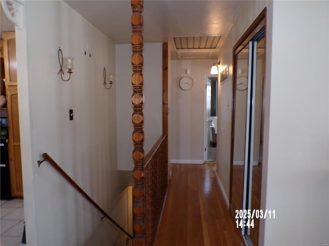 hallway with an upstairs landing, light wood finished floors, and baseboards