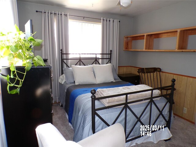 carpeted bedroom with wood walls and wainscoting