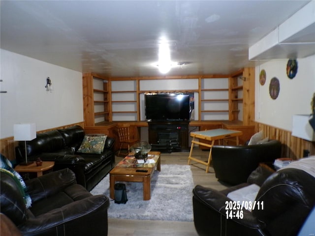 living area with wooden walls, wainscoting, and wood finished floors