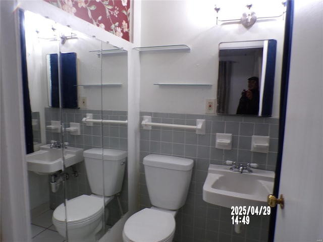 bathroom with a sink, tile walls, a wainscoted wall, and toilet
