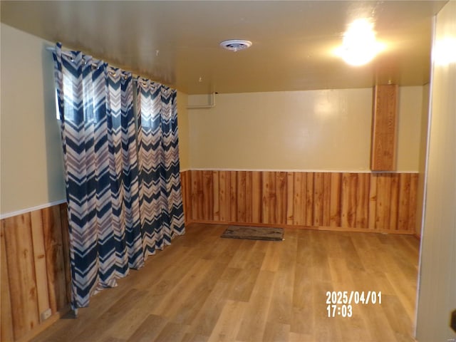 finished basement with wainscoting, wood walls, and light wood-style flooring