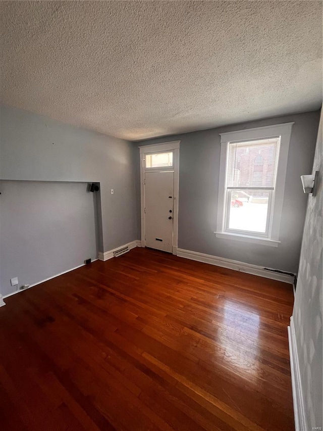 entrance foyer featuring visible vents, baseboards, a textured ceiling, and wood finished floors