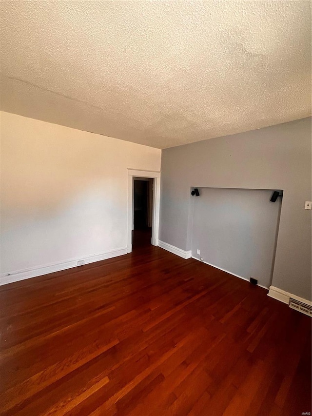 spare room featuring visible vents, dark wood-style floors, baseboards, and a textured ceiling