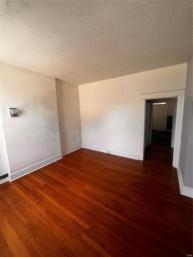 unfurnished room with wood finished floors, baseboards, and a textured ceiling