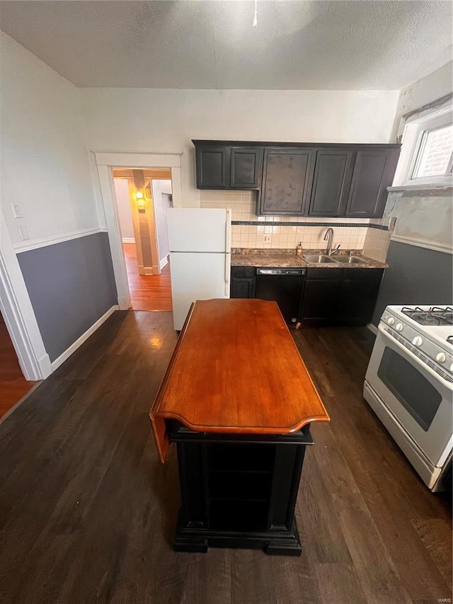 kitchen featuring white appliances, a sink, dark wood-type flooring, a textured ceiling, and tasteful backsplash