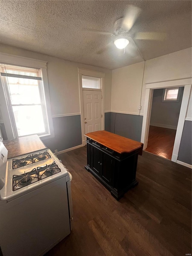 kitchen featuring dark cabinetry, white gas stove, dark wood-type flooring, and a textured ceiling