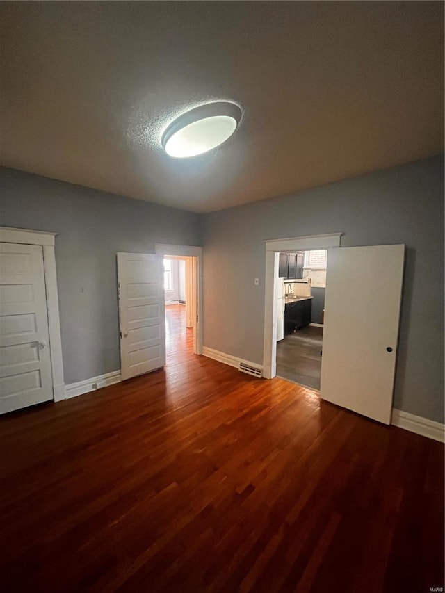 empty room with plenty of natural light, wood finished floors, and visible vents