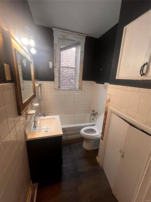 bathroom featuring tile walls, toilet, wainscoting, a bath, and vanity