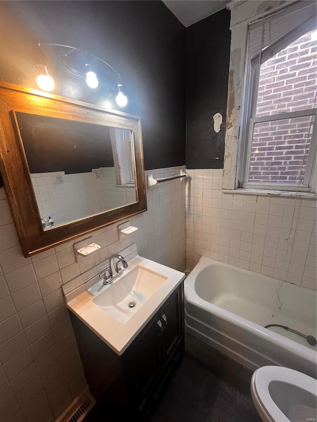 bathroom featuring vanity, tile walls, toilet, and a washtub