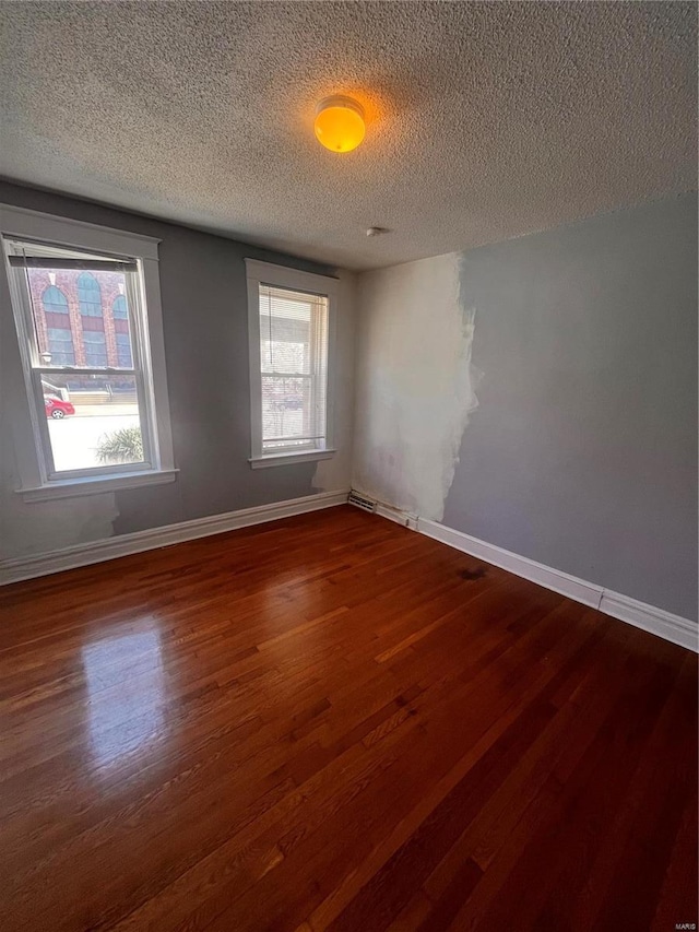 unfurnished room with dark wood finished floors, baseboards, and a textured ceiling