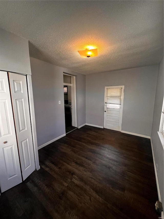 unfurnished bedroom featuring wood finished floors, baseboards, a closet, and a textured ceiling