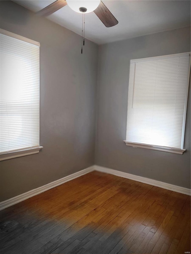 empty room featuring a ceiling fan, baseboards, and wood-type flooring