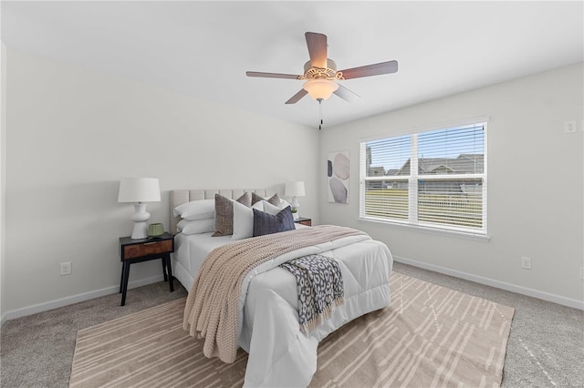 bedroom with light colored carpet, a ceiling fan, and baseboards