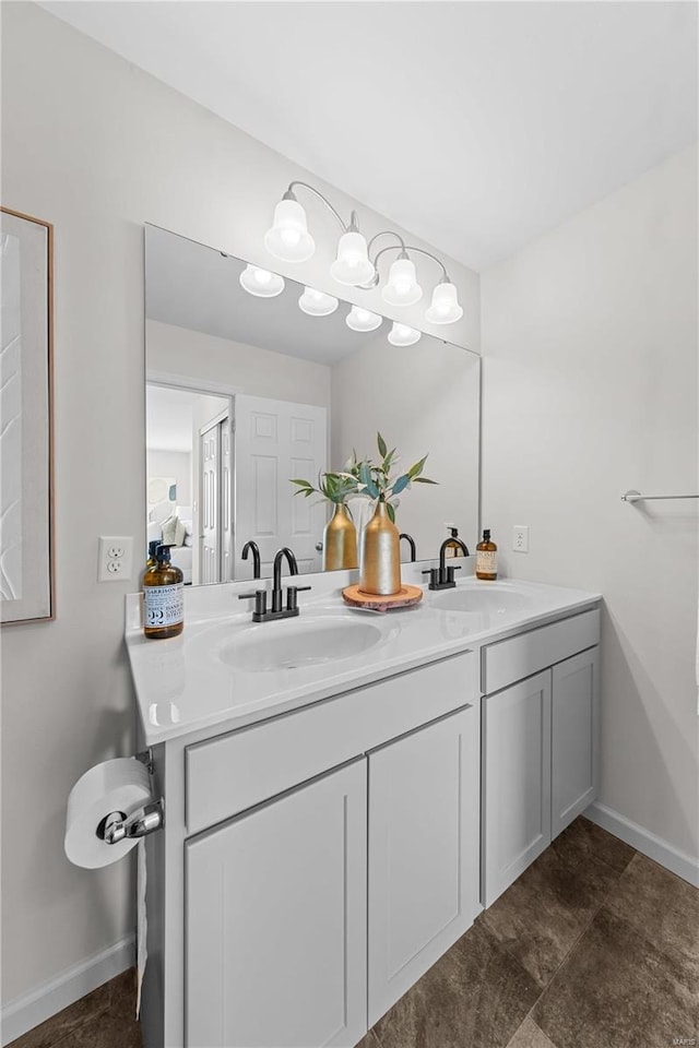 bathroom featuring a sink, baseboards, and double vanity