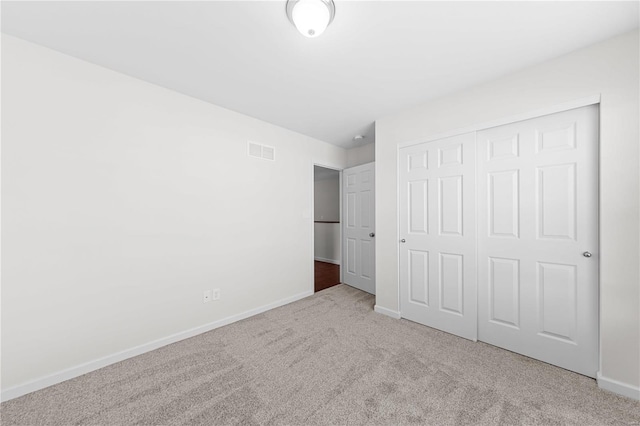 unfurnished bedroom with carpet, visible vents, a closet, and baseboards