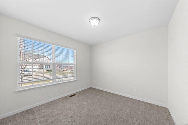 unfurnished room featuring visible vents, baseboards, and carpet