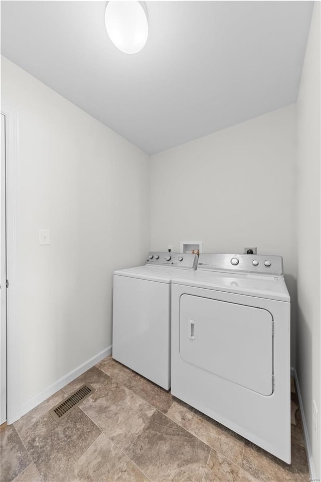 washroom with visible vents, washer and dryer, laundry area, and baseboards