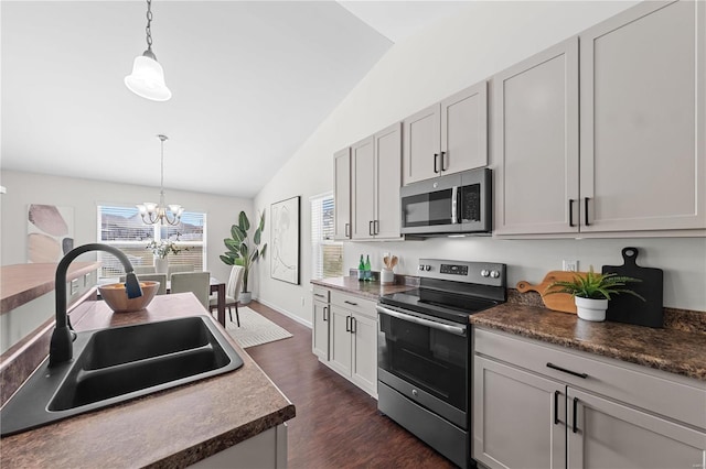 kitchen featuring a sink, appliances with stainless steel finishes, an inviting chandelier, vaulted ceiling, and hanging light fixtures