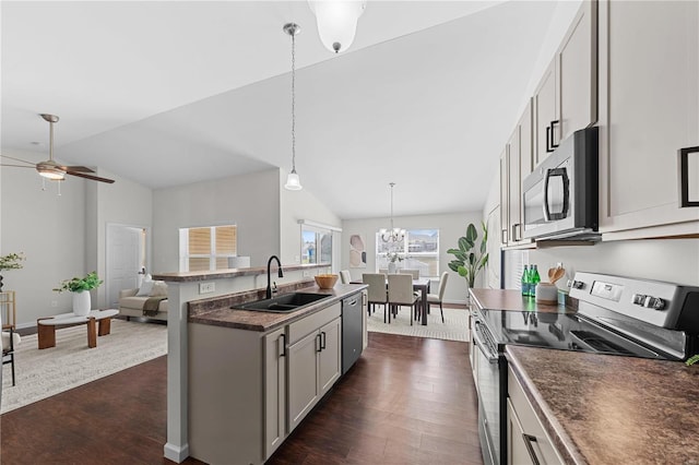 kitchen featuring dark wood-style flooring, a sink, stainless steel appliances, dark countertops, and open floor plan