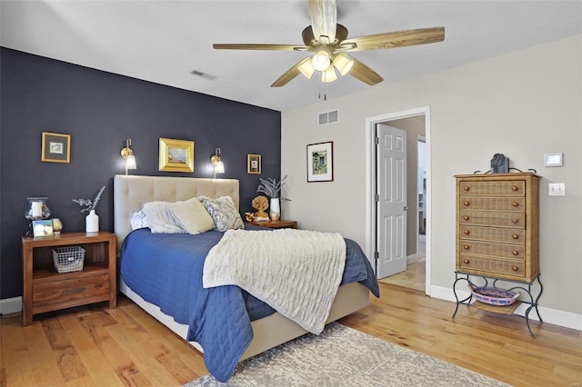 bedroom featuring baseboards, visible vents, light wood finished floors, and ceiling fan