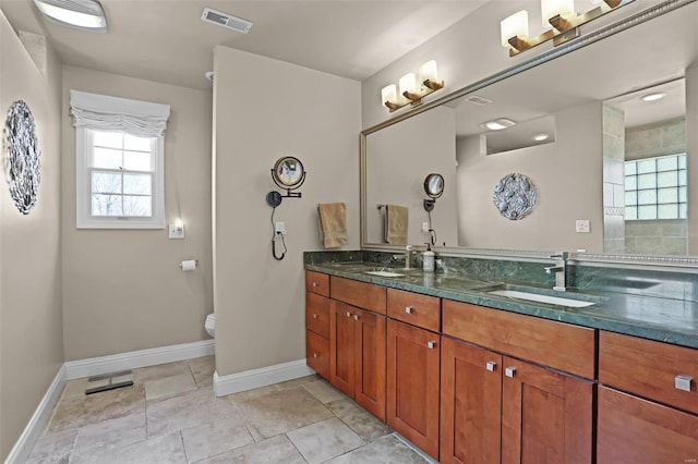 full bathroom with double vanity, baseboards, visible vents, and a sink