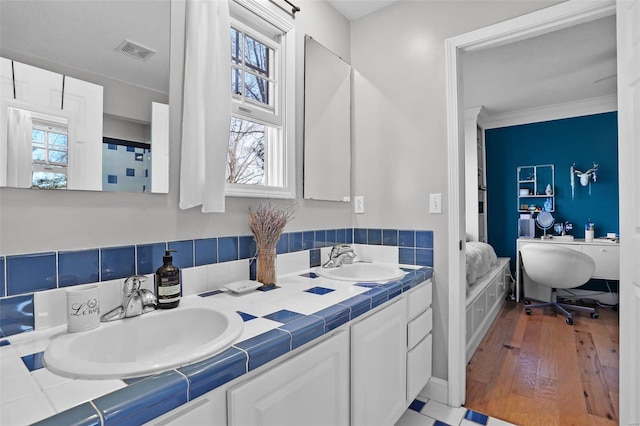 full bath with double vanity, visible vents, wood finished floors, and a sink