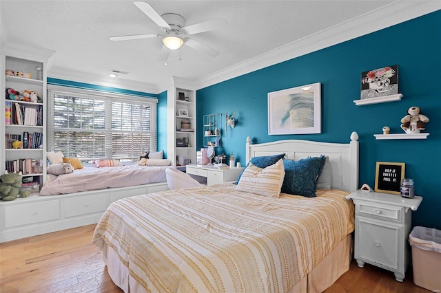 bedroom featuring crown molding, wood finished floors, visible vents, and ceiling fan