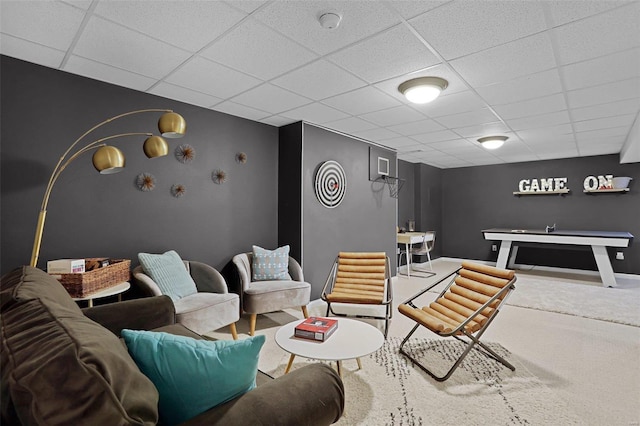 living area with baseboards, a paneled ceiling, and carpet