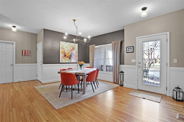 dining space with a notable chandelier, wainscoting, and wood-type flooring