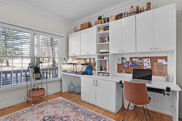 office space featuring visible vents, baseboards, light wood-style floors, and crown molding