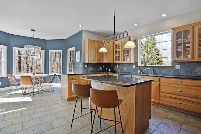 kitchen with decorative backsplash, a breakfast bar area, a center island, and a sink