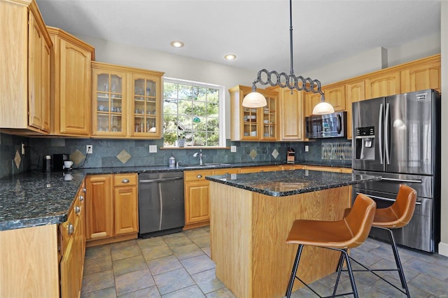 kitchen featuring backsplash, glass insert cabinets, a breakfast bar area, appliances with stainless steel finishes, and a sink