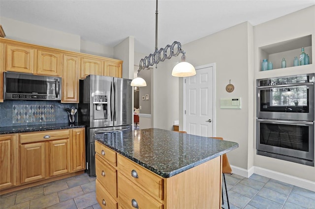 kitchen with a kitchen island, stainless steel appliances, dark stone counters, a breakfast bar area, and decorative backsplash