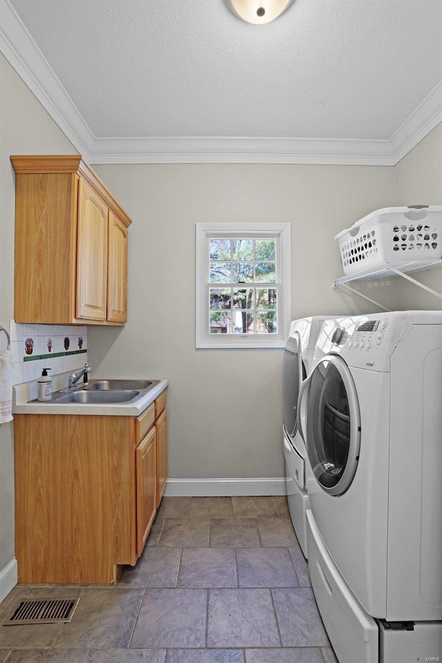 clothes washing area featuring baseboards, visible vents, a sink, stone tile flooring, and washer and clothes dryer