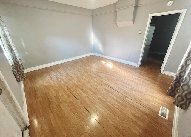 spare room featuring visible vents, baseboards, and wood finished floors