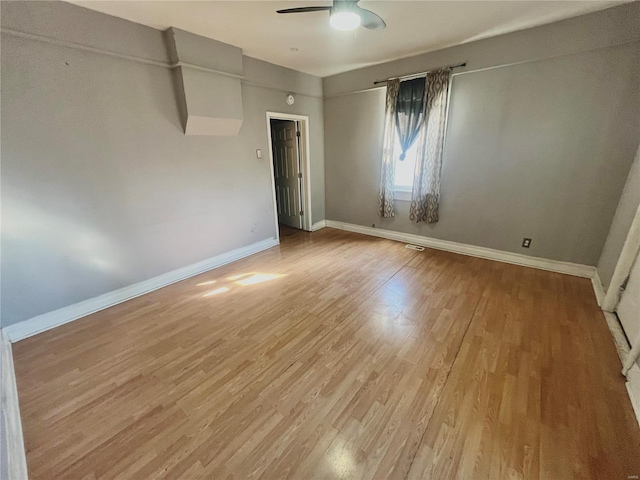 empty room featuring light wood-style flooring, a ceiling fan, and baseboards