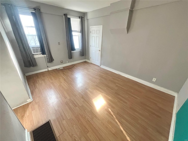 empty room with a wealth of natural light, visible vents, baseboards, and light wood finished floors