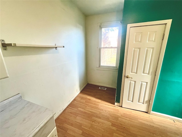 corridor featuring visible vents, baseboards, and light wood finished floors