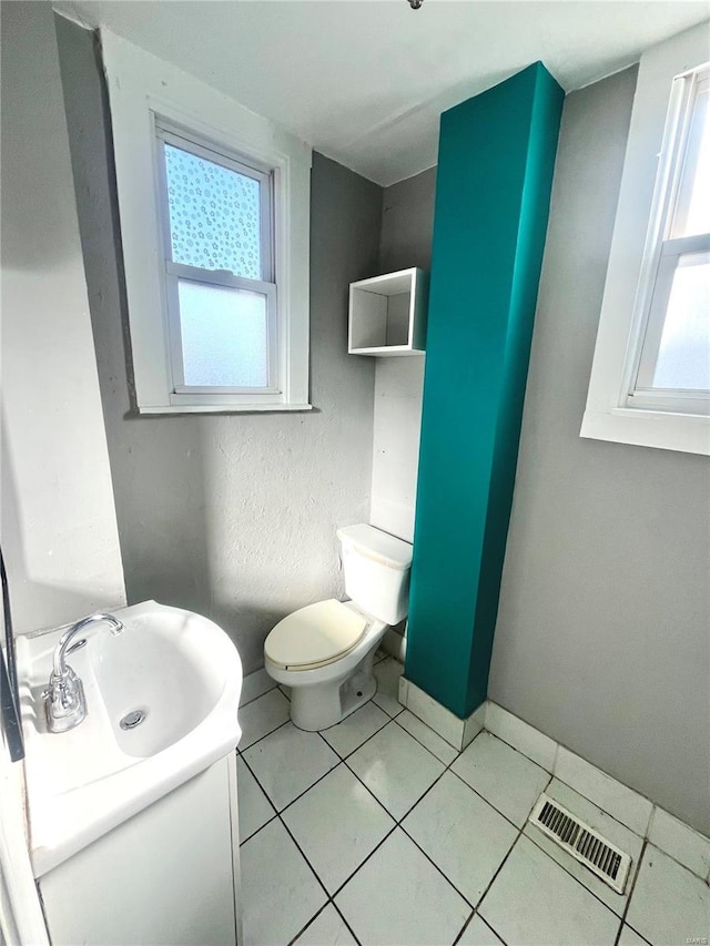 half bathroom featuring tile patterned flooring, visible vents, baseboards, toilet, and vanity